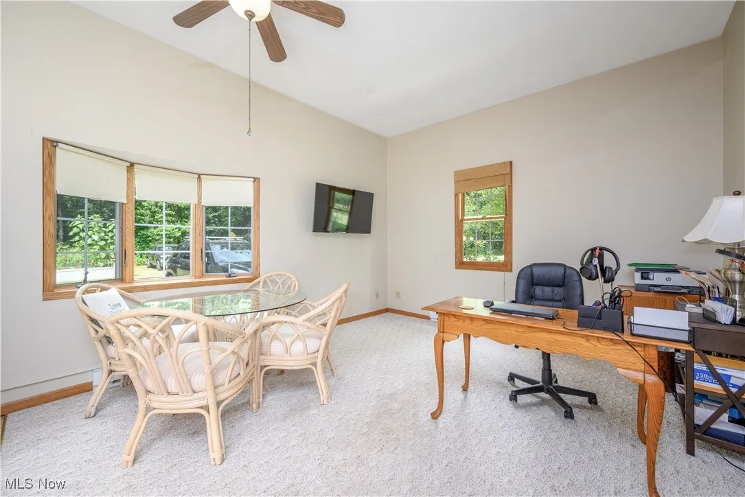 Carpeted home office with a ceiling fan and baseboards