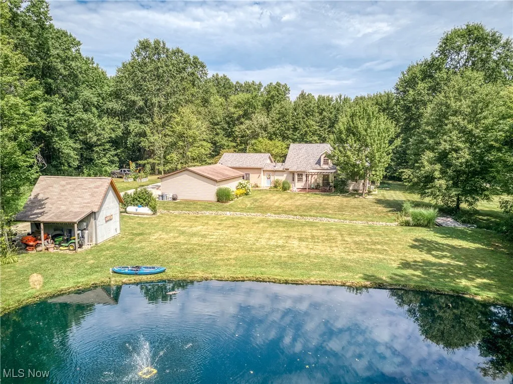 Aerial view of property and surrounding area with a large body of water and a heavily wooded area