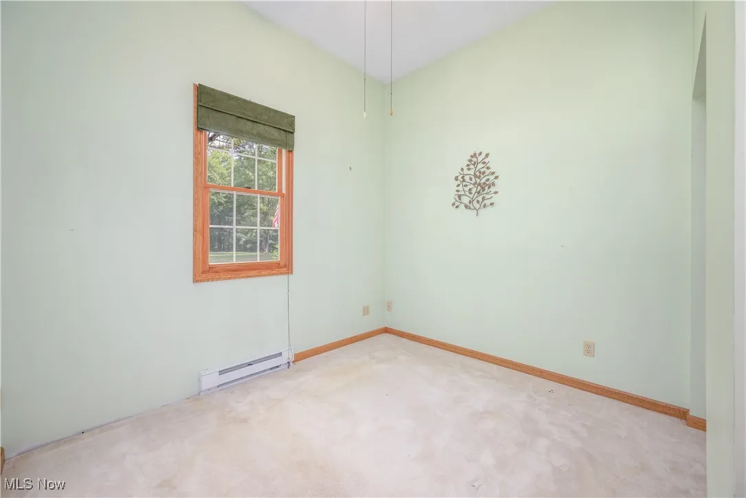 Empty room with baseboard heating and light carpet