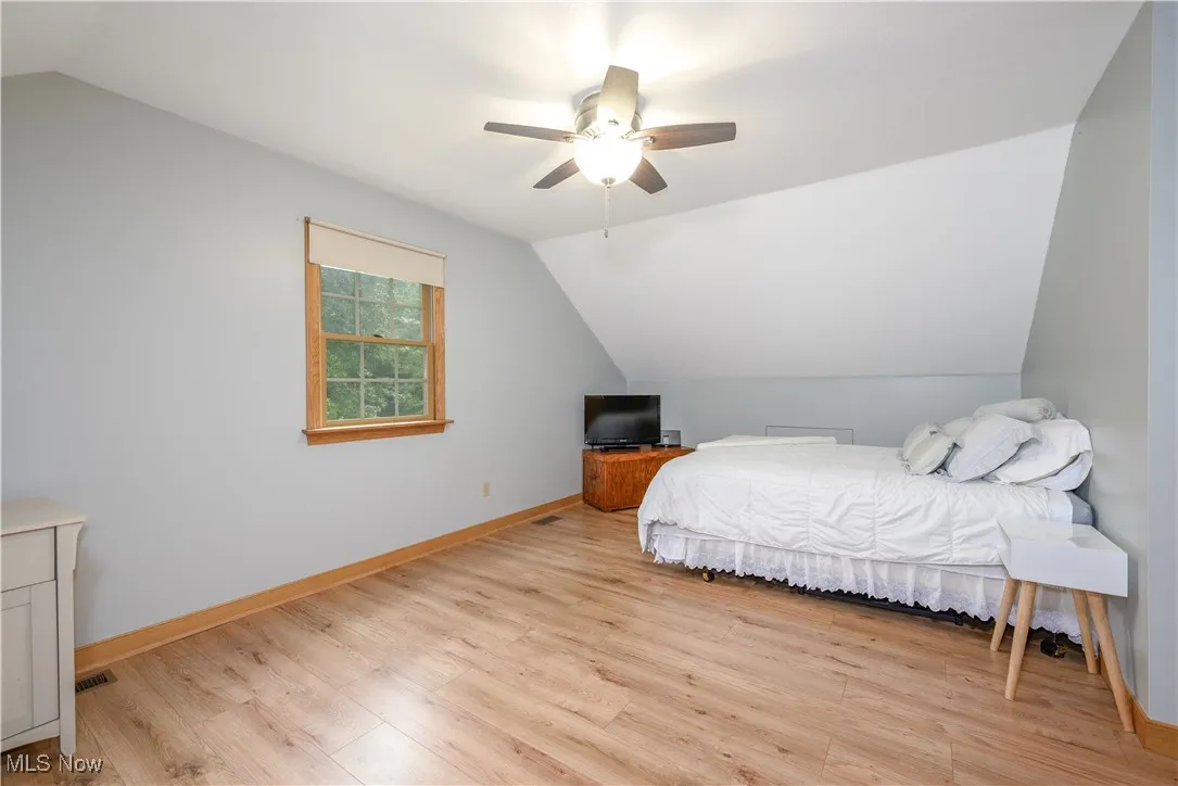 Bedroom with lofted ceiling, light wood-style flooring, and ceiling fan