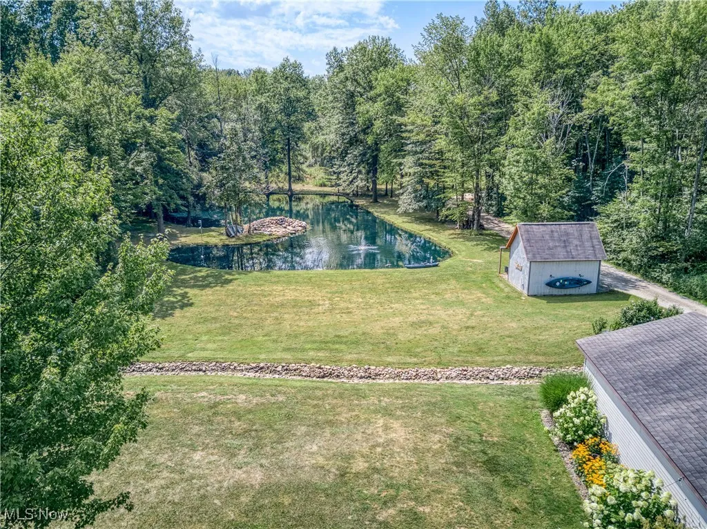 View of green lawn featuring an outdoor structure, a water view, and a forest view