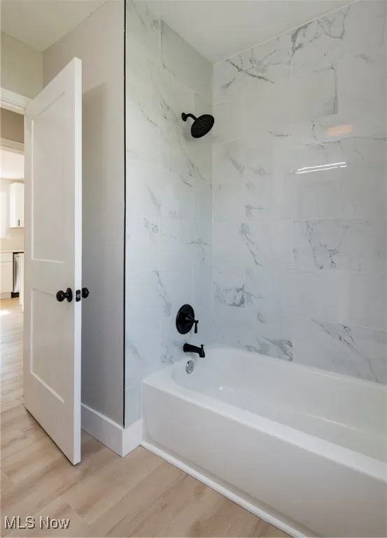 Bathroom featuring wood finished floors and bathing tub / shower combination