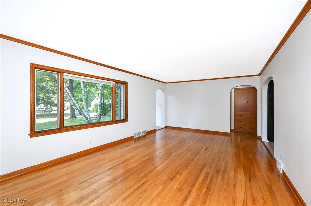 *LARGE LIVING ROOM W/SHINY HARDWOOD FLOORS, FEATURE WALL, CROWN MOLDING, STONE SURROUND FIREPLACE AND TILED HEARTH. ARCHED ENTRYWAY TO THE EAT IN KITCHEN AND BEDROOMS ~