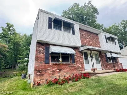 View of front of home with a front lawn, brick siding, and a garage