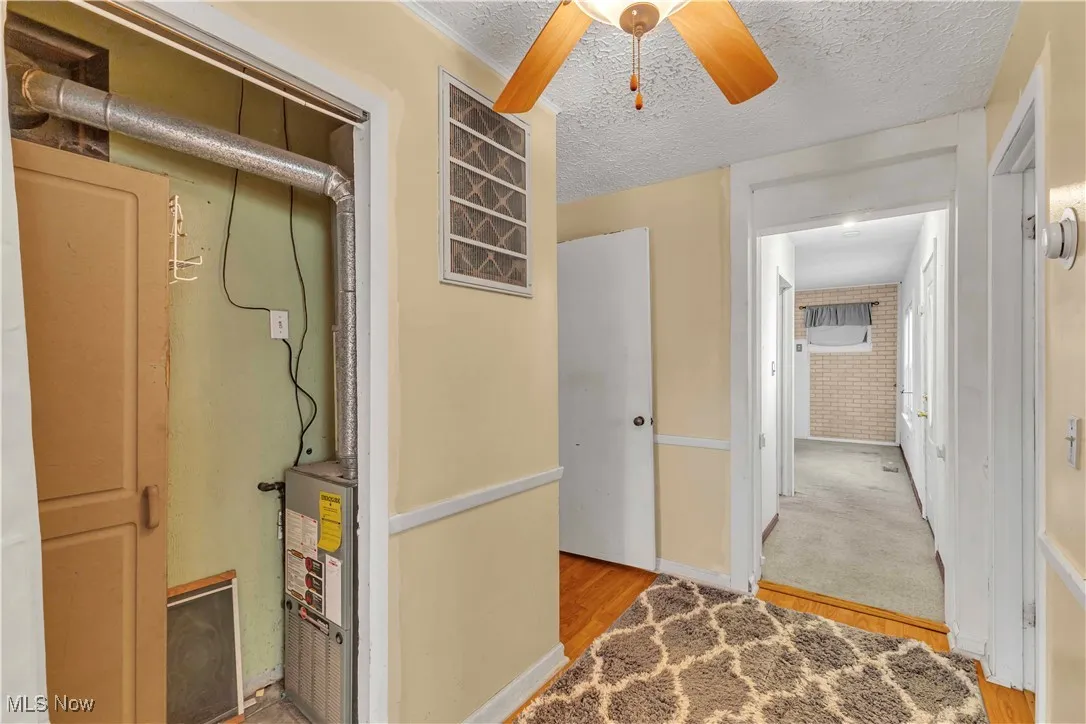 Hallway with light wood-style floors and a textured ceiling