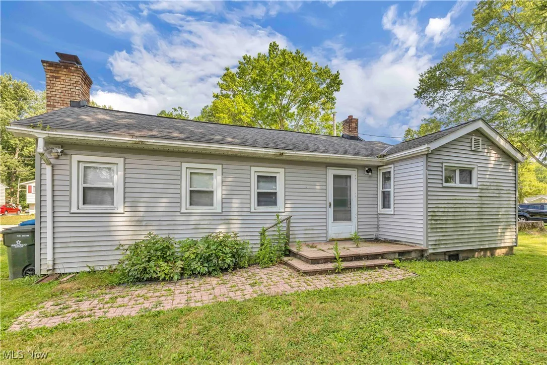 Back of property with a chimney, a yard, roof with shingles, and a deck