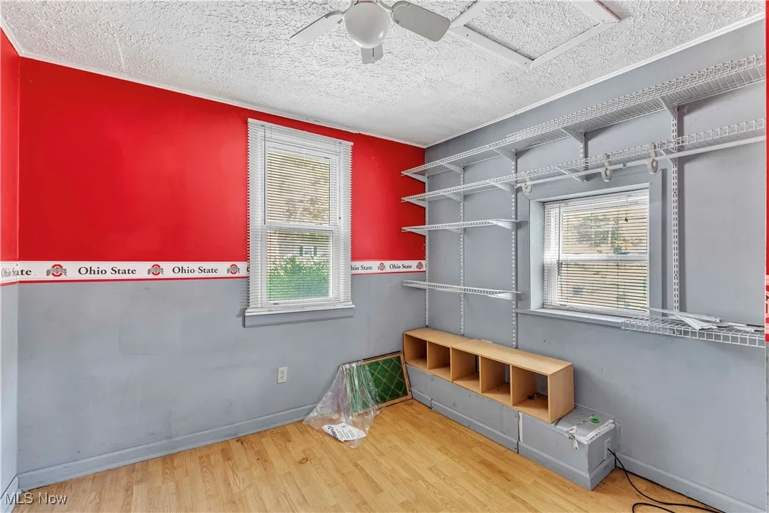 Unfurnished bedroom featuring wood finished floors, a textured ceiling, and a ceiling fan