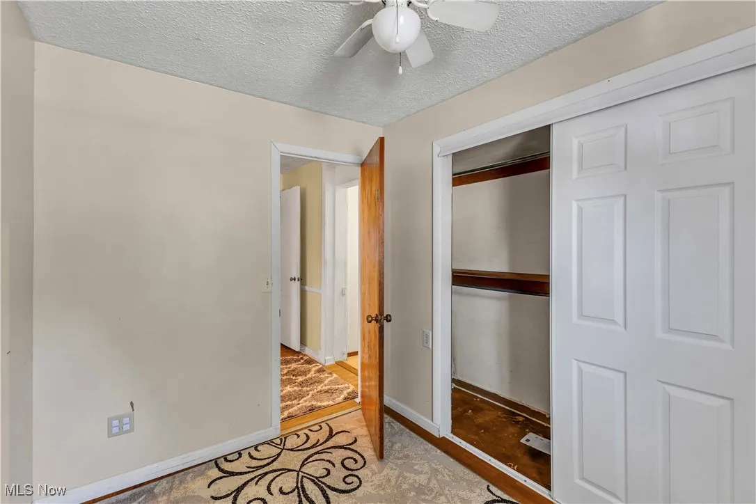 Unfurnished bedroom featuring a textured ceiling, a closet, and ceiling fan