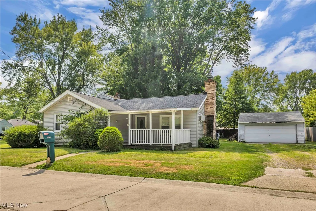 View of front of property with a porch, an outbuilding, a front lawn, and a chimney
