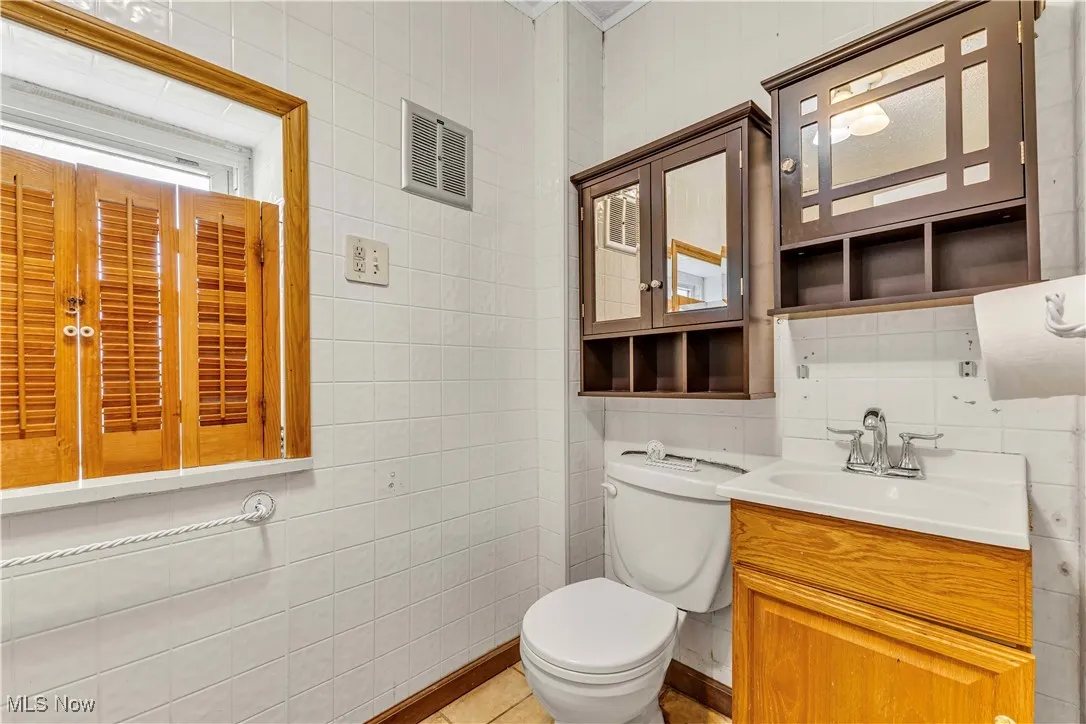 Bathroom featuring tile walls, vanity, and tile patterned floors