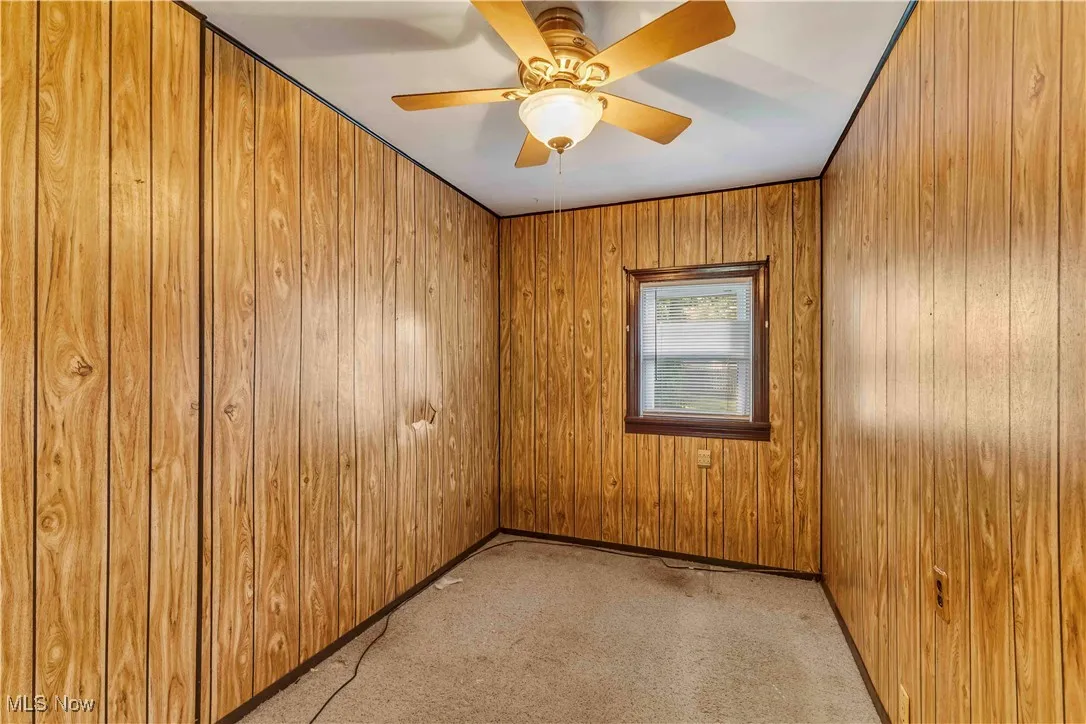 Unfurnished room with light carpet and wooden walls
