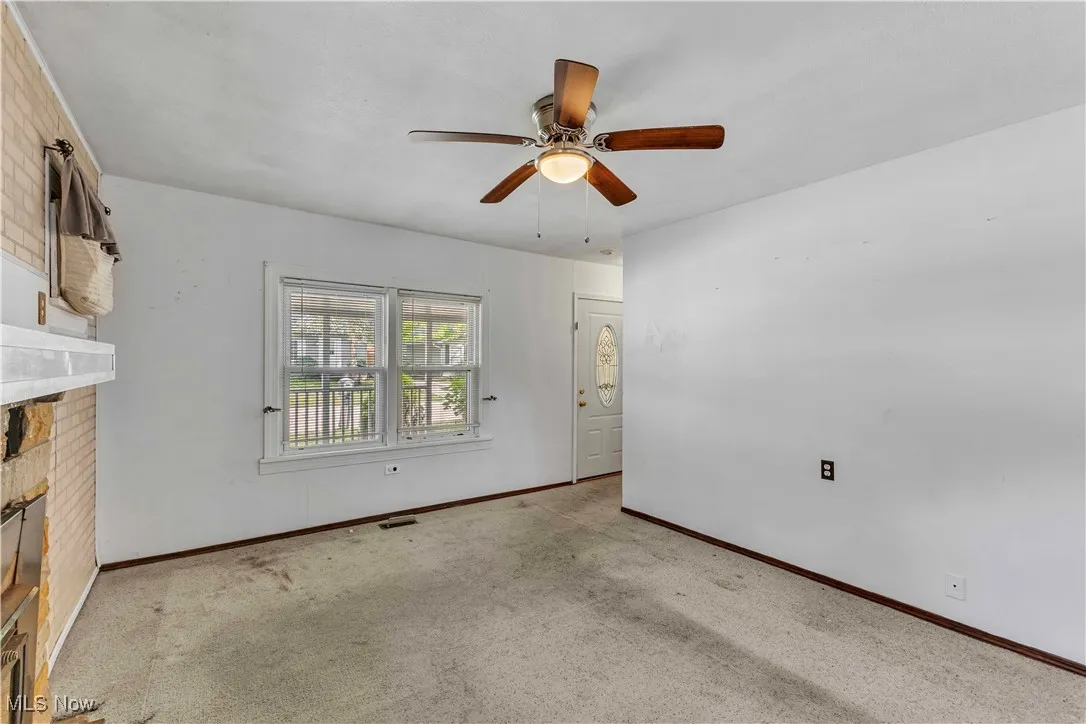 Unfurnished living room featuring carpet, a ceiling fan, and a fireplace
