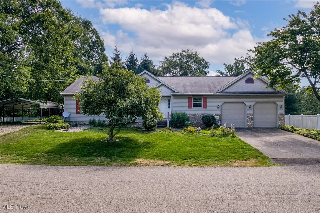 Single story home featuring driveway, a front lawn, stone siding, and an attached garage