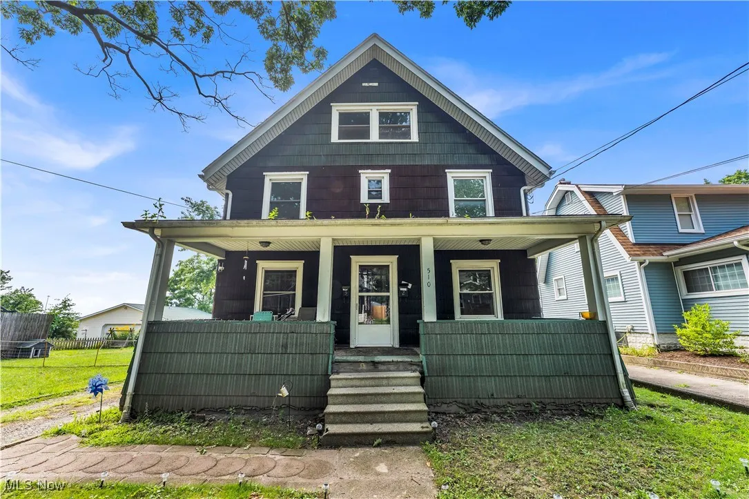 Traditional style home featuring covered porch and a front yard