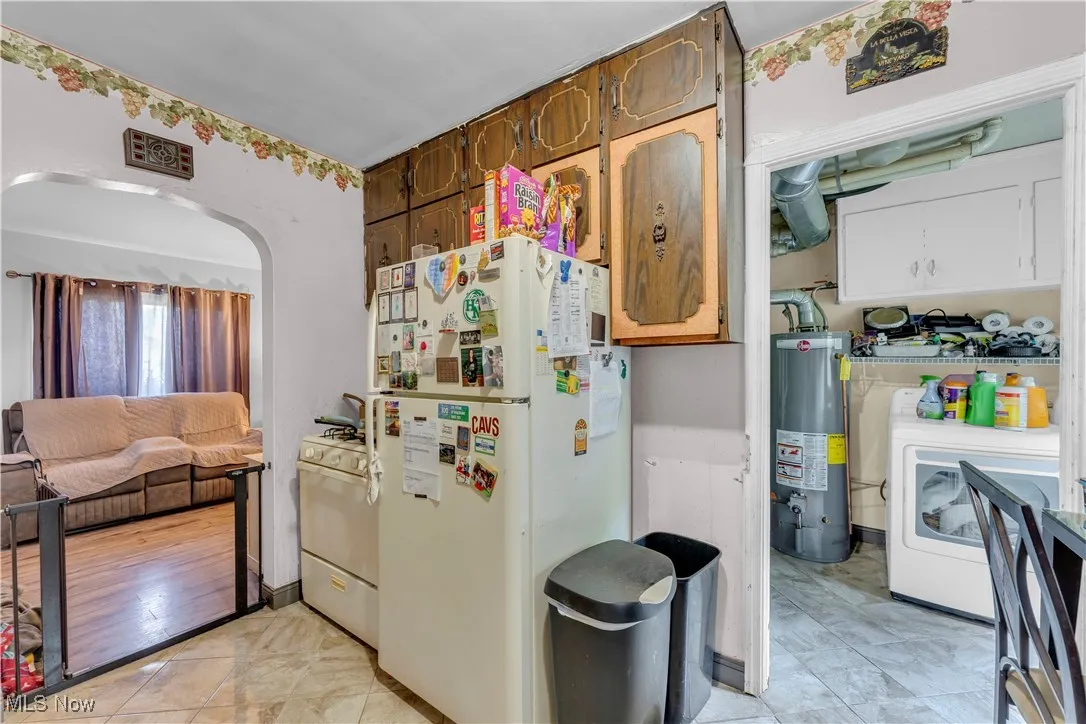 Kitchen with white appliances, arched walkways, light countertops, and light tile patterned floors