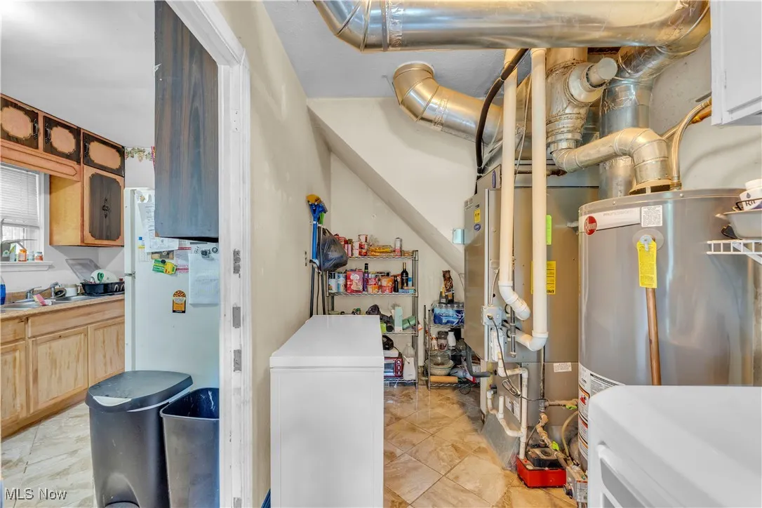 Laundry area featuring cabinet space, separate washer and dryer, water heater, and light tile patterned floors