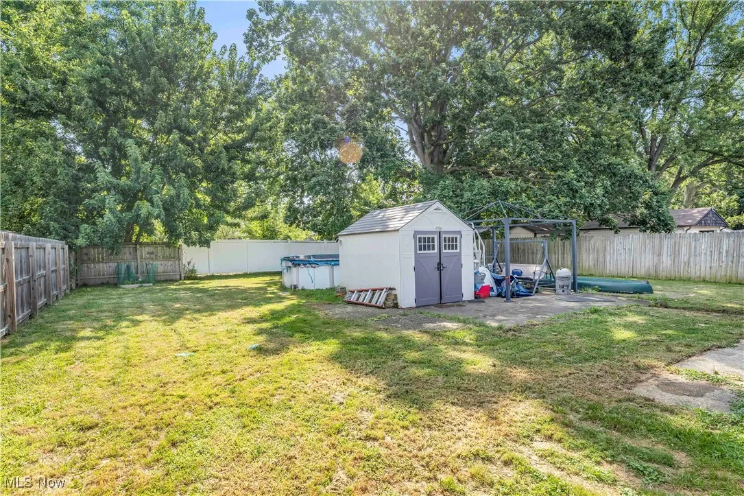 Fenced backyard with view of wooded area and a shed