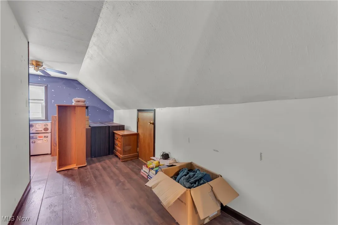 Additional living space featuring wood finished floors, lofted ceiling, and a textured ceiling