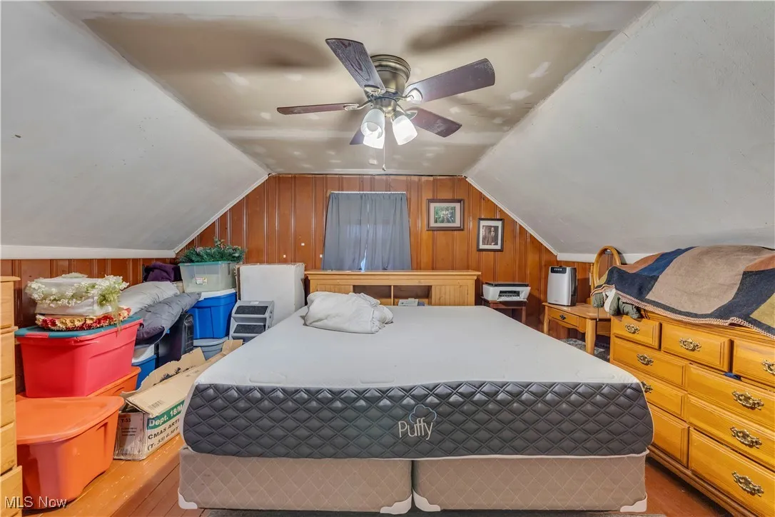 Bedroom with wooden walls, vaulted ceiling, and wood finished floors