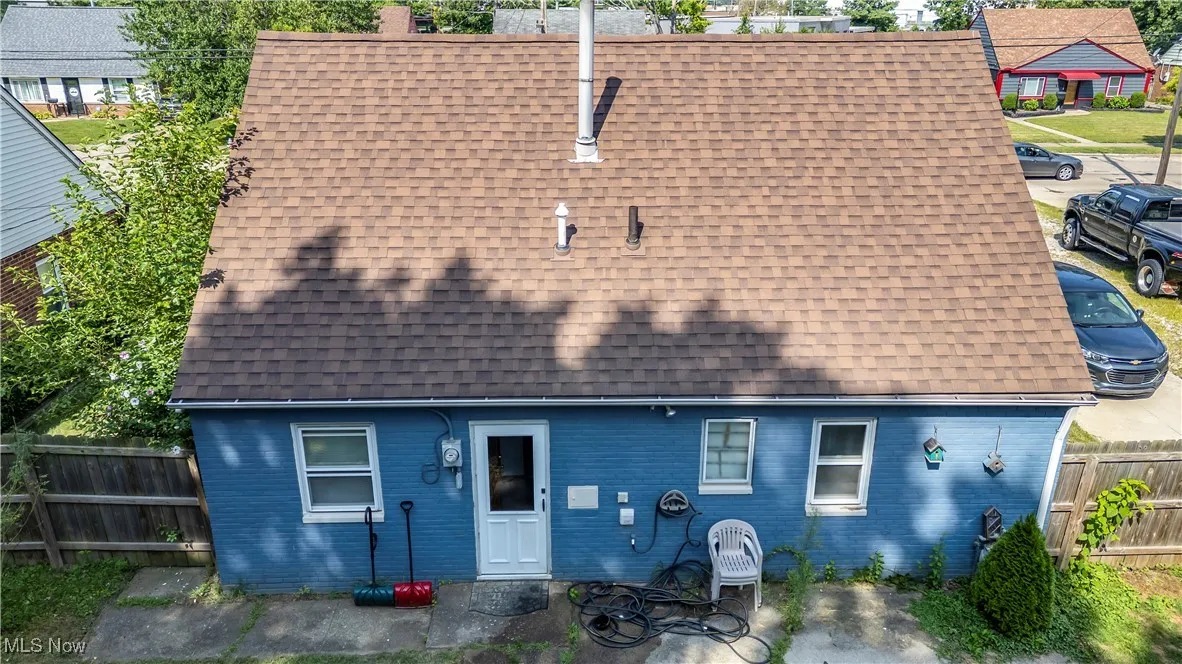 Rear view of house with roof with shingles, a patio, and brick siding