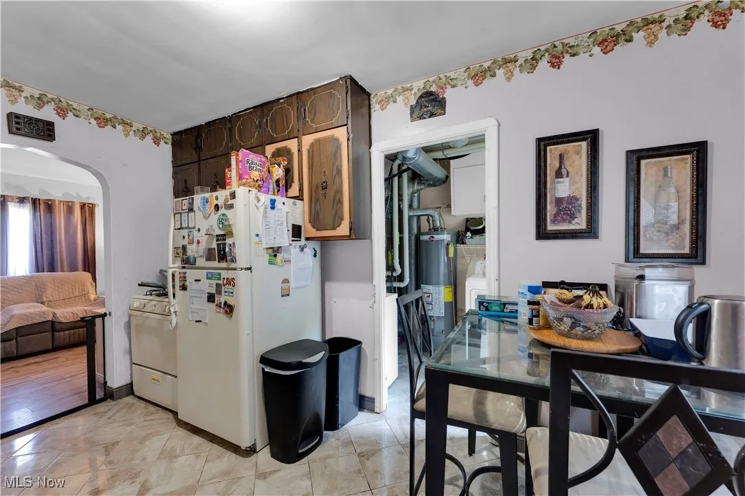 Kitchen featuring white range with gas cooktop, light countertops, light tile patterned floors, and stainless steel microwave
