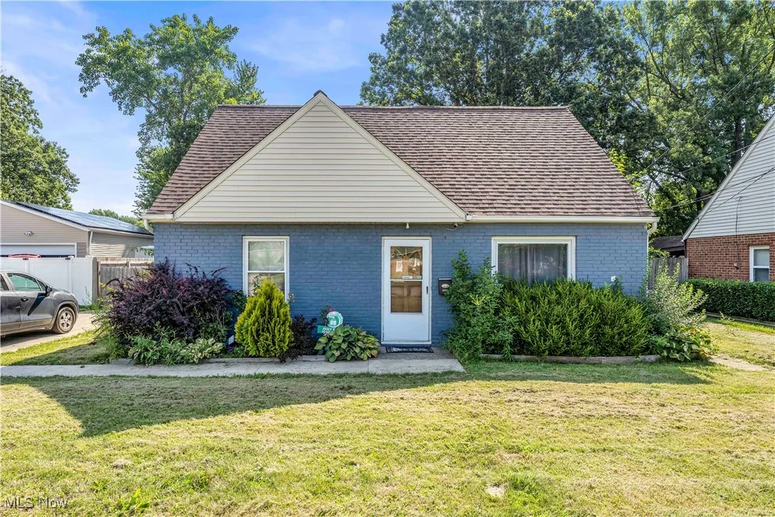 View of front of home featuring brick siding and roof with shingles