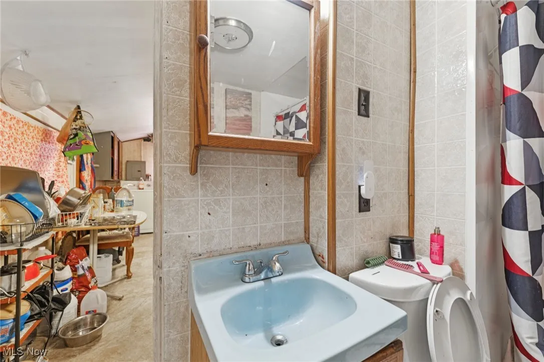 Bathroom featuring tile walls, vanity, and washer / clothes dryer