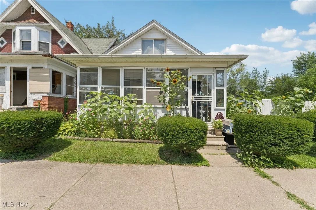 View of front of property with a sunroom, brick siding, and a chimney