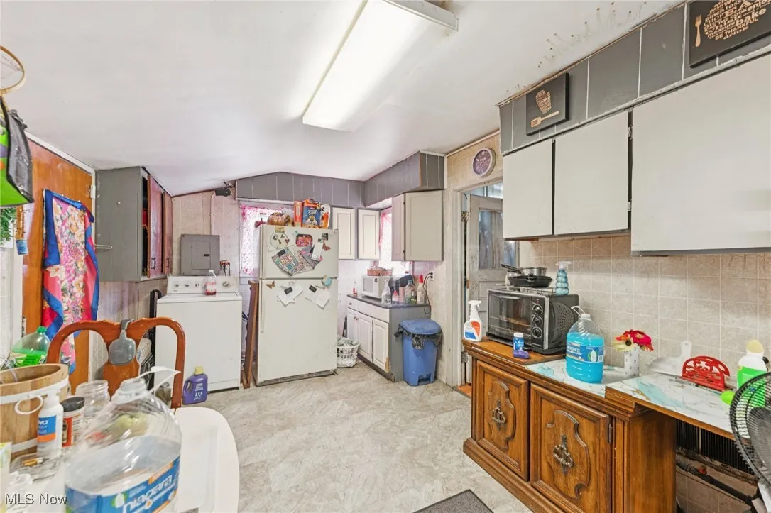 Kitchen featuring freestanding refrigerator, vaulted ceiling, and electric panel