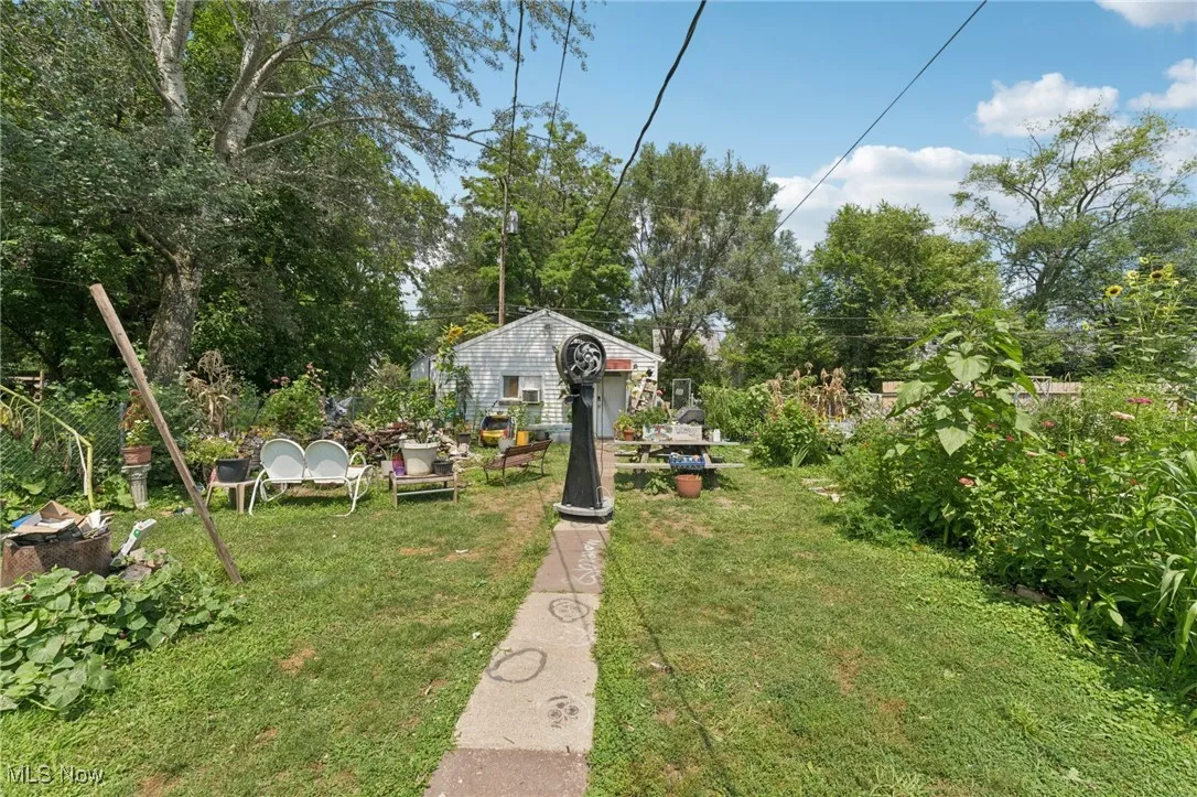 View of green lawn featuring view of scattered trees and an outbuilding
