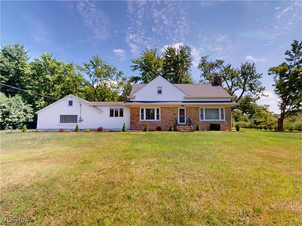 View of front of property featuring a chimney, a front yard, and brick siding