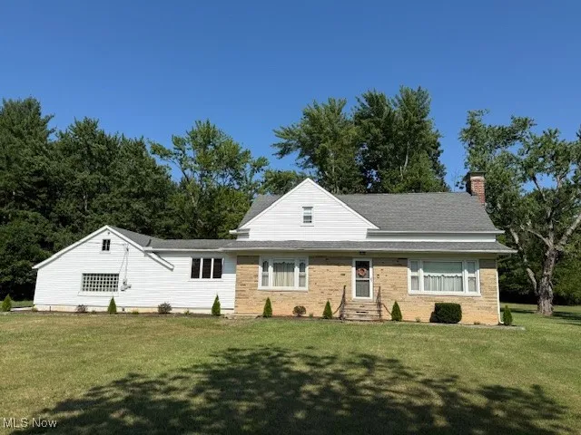 View of front facade featuring a chimney, a front yard, and brick siding