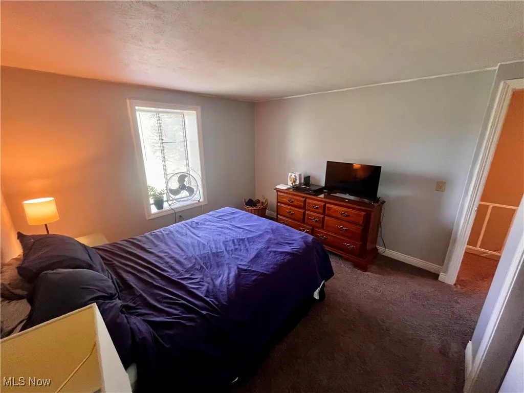 Bedroom featuring dark colored carpet and a textured ceiling