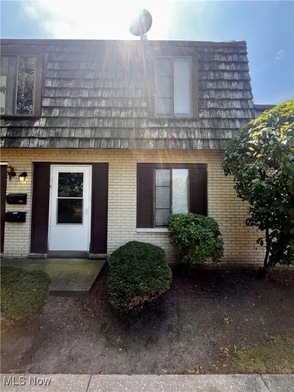 Doorway to property featuring brick siding, mansard roof, and a patio area