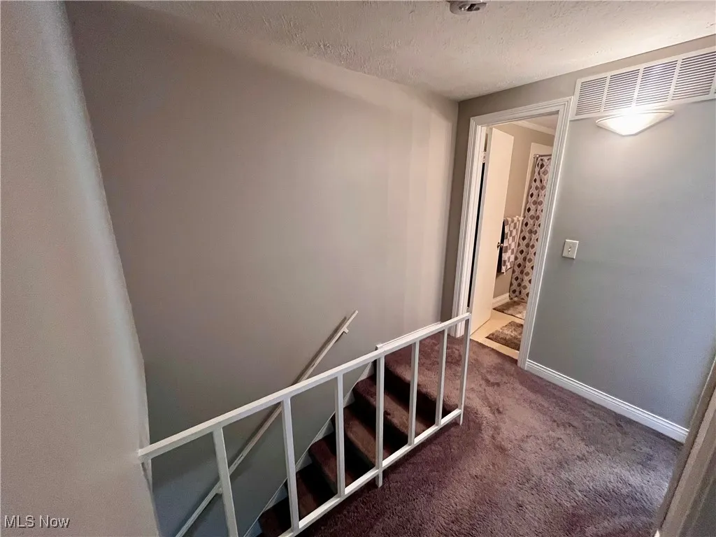 Stairs featuring a textured ceiling and carpet floors