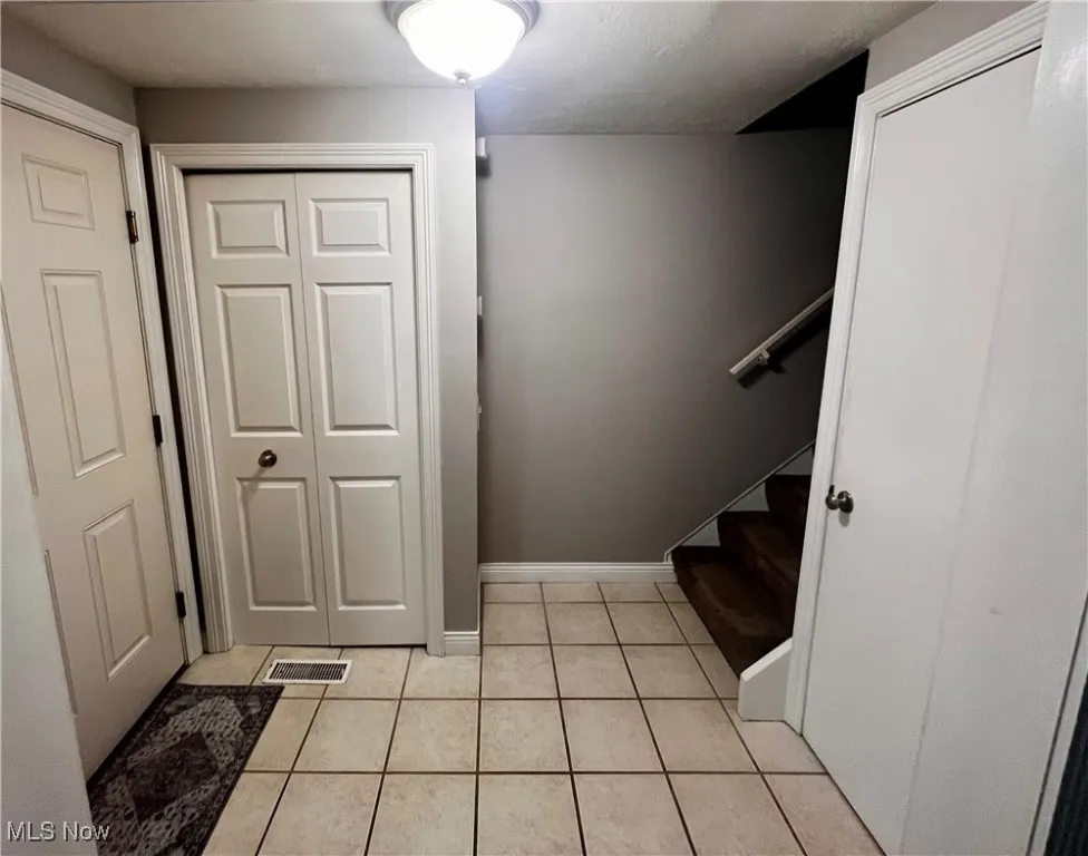 Entryway with light tile patterned floors and stairs