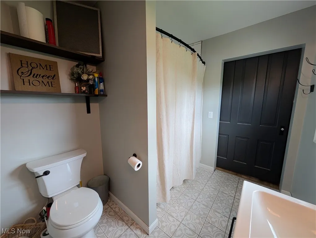 Full bath featuring curtained shower and tile patterned floors