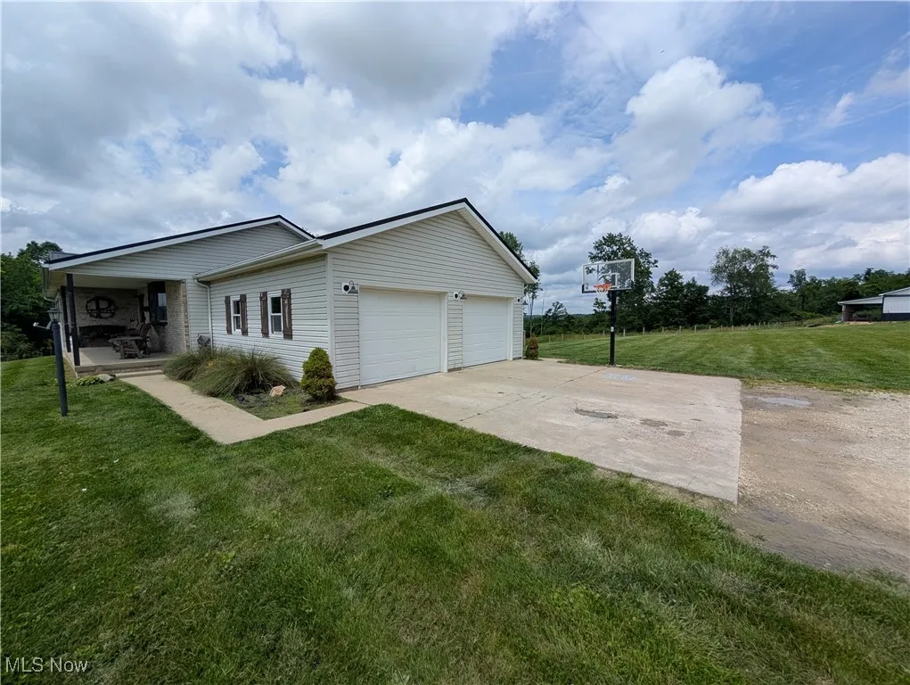 View of property exterior featuring a lawn, an attached garage, and concrete driveway