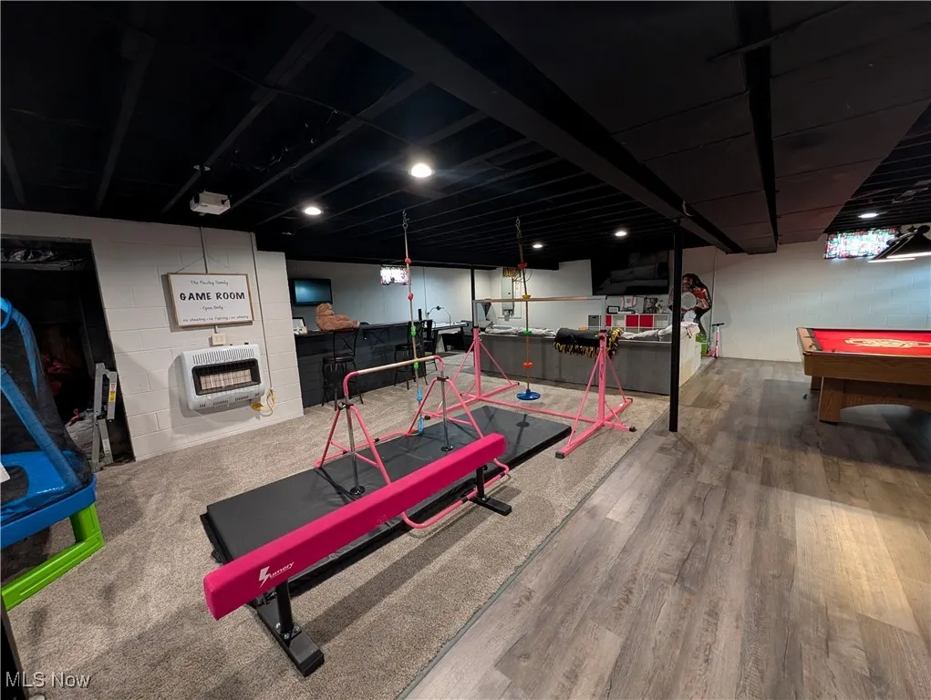 Workout room with heating unit, billiards, and wood finished floors