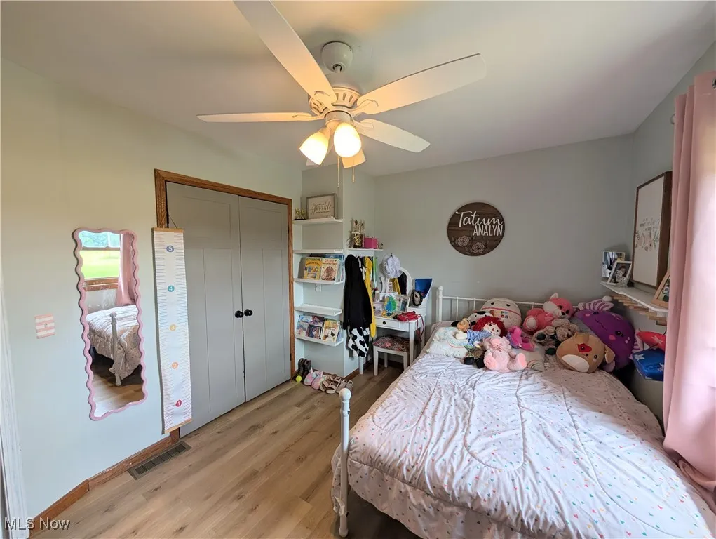 Bedroom with light wood-type flooring, a ceiling fan, and a closet