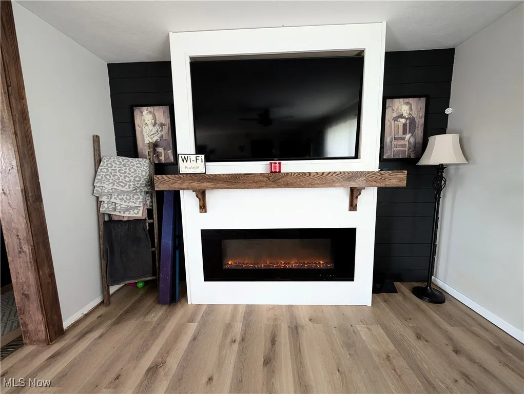 Detailed view of wood finished floors, a glass covered fireplace, and wood walls