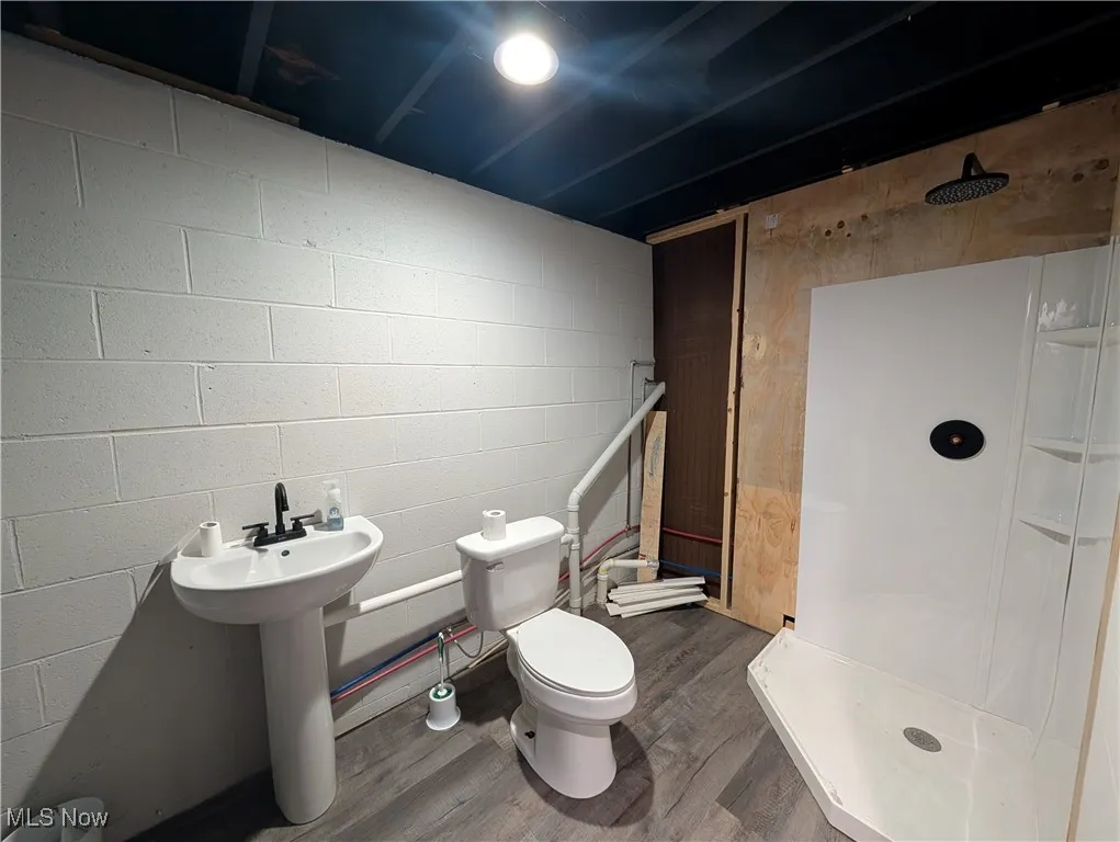 Full bathroom featuring a stall shower and wood finished floors