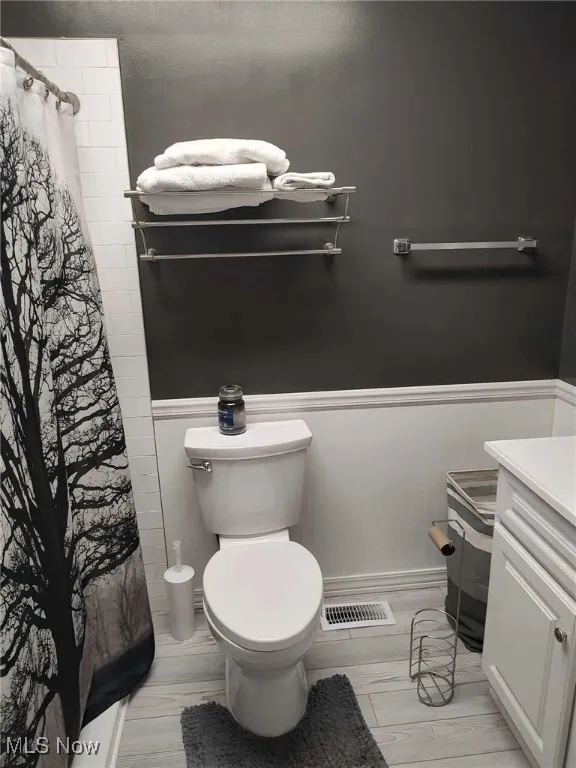 Bathroom with vanity, a wainscoted wall, curtained shower, and wood finished floors