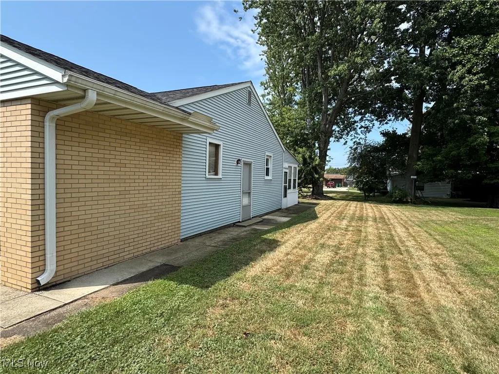 View of side of home with a lawn, brick siding, and a shingled roof