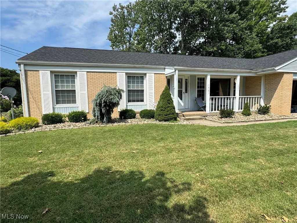 Single story home with brick siding, a front yard, a shingled roof, and a porch