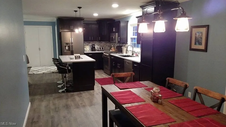 Kitchen with stainless steel appliances, decorative backsplash, a center island, light countertops, and light wood finished floors