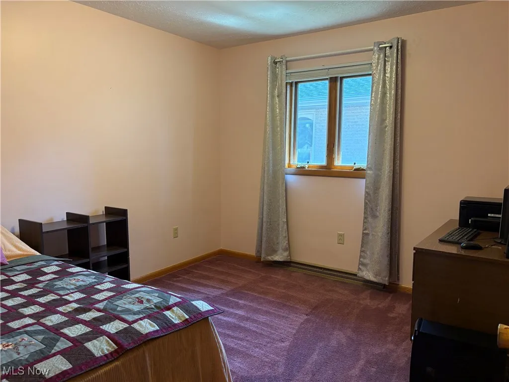 Carpeted bedroom with a textured ceiling and a desk