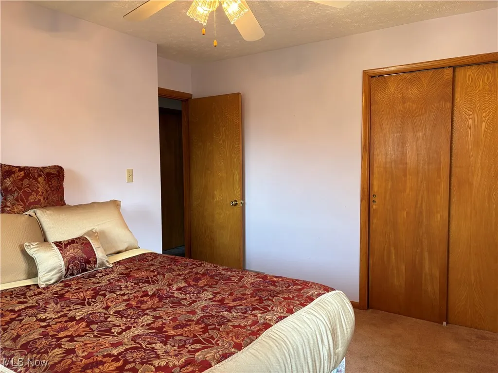 Carpeted bedroom featuring a textured ceiling, a closet, and a ceiling fan