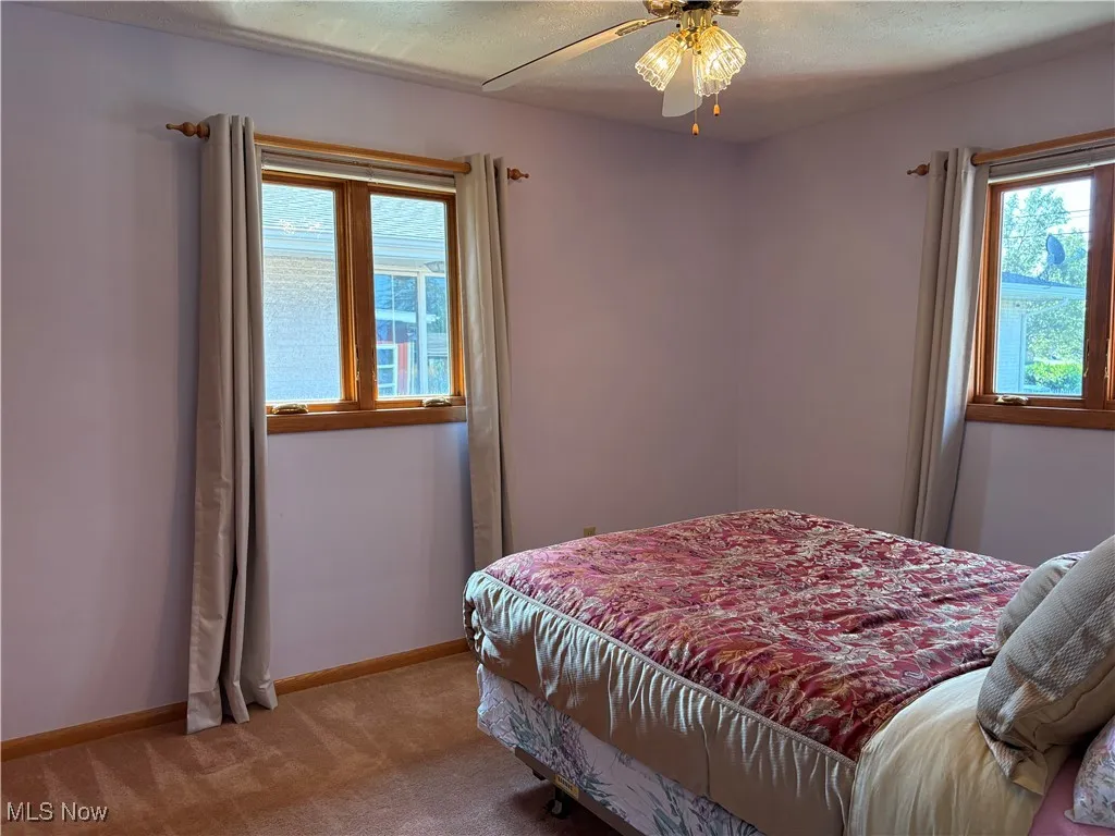Bedroom with carpet, a ceiling fan, and a textured ceiling