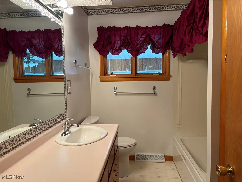 Full bath with healthy amount of natural light, vanity, and tile patterned flooring